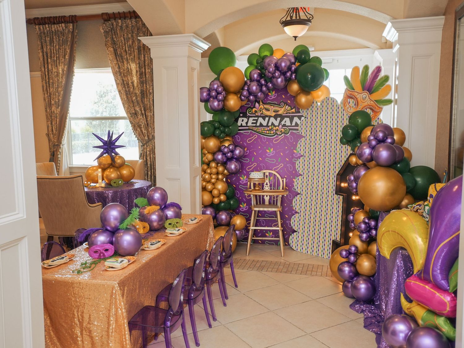 Luxurious party space decorated with purple and gold balloon garlands and coordinating furniture.