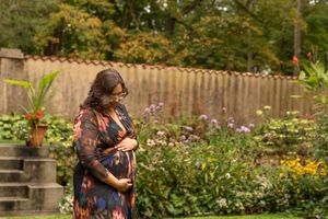 A person in a floral dress walks through a vibrant garden filled with colorful summer blooms and greenery.