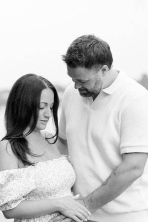 Couple shares an intimate moment in black and white photography wearing light colored clothing.