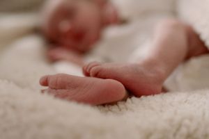 Tiny baby feet resting on soft white textured fabric in close-up view.