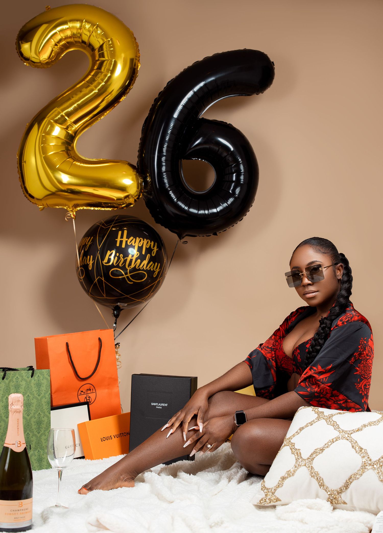 Stylish birthday photo with gold 26 balloons, luxury shopping bags and elegant decor.