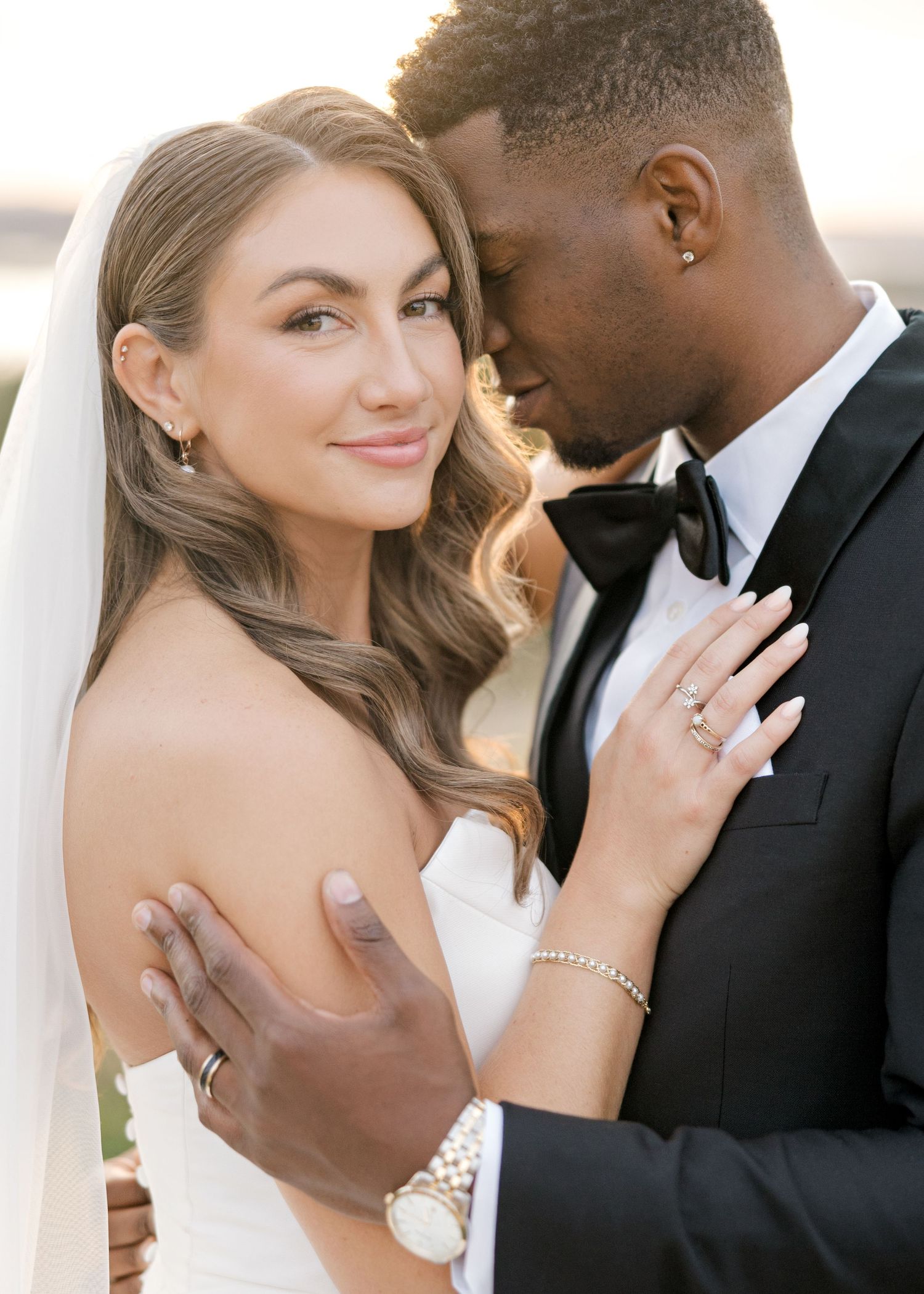 bride and groom on wedding day. groom has forehead resting on bride while bride looks at camera smiling