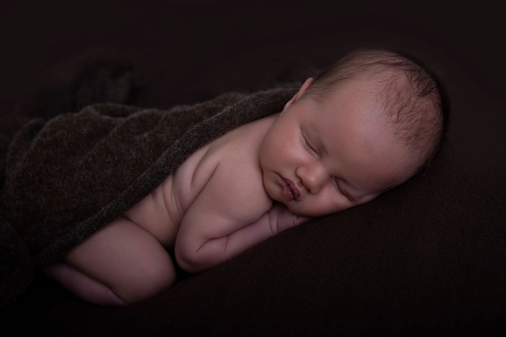Professional newborn portrait in Gilston home studio with soft cream textures.