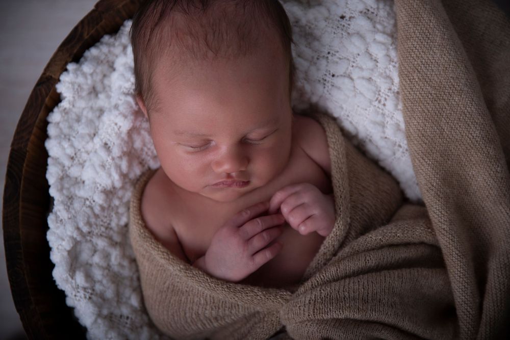 Newborn photographer Gold Coast safely posing baby in neutral wrap.