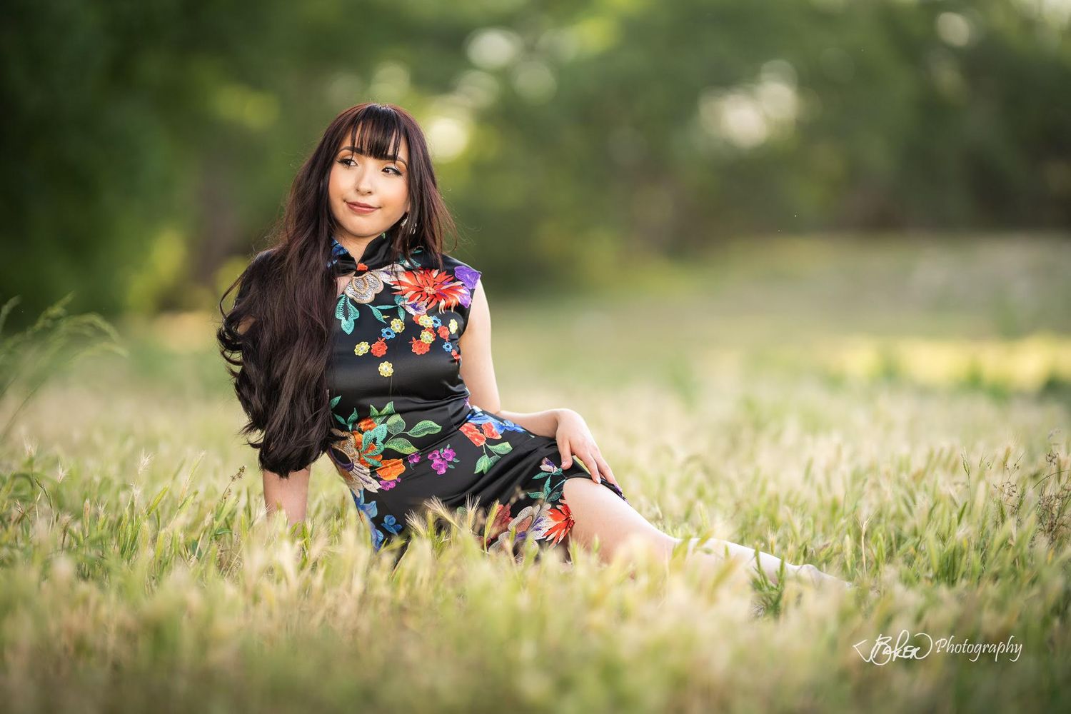 A person in a floral dress sits in a sunlit meadow with soft bokeh effect in the background.