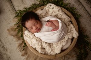 baby boy curled up in a bowl during his newborn photography session