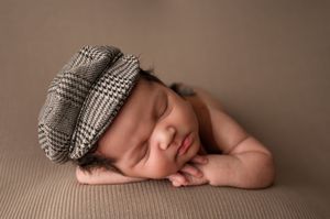 newborn boy posed with chin on hands during a newborn photoshoot