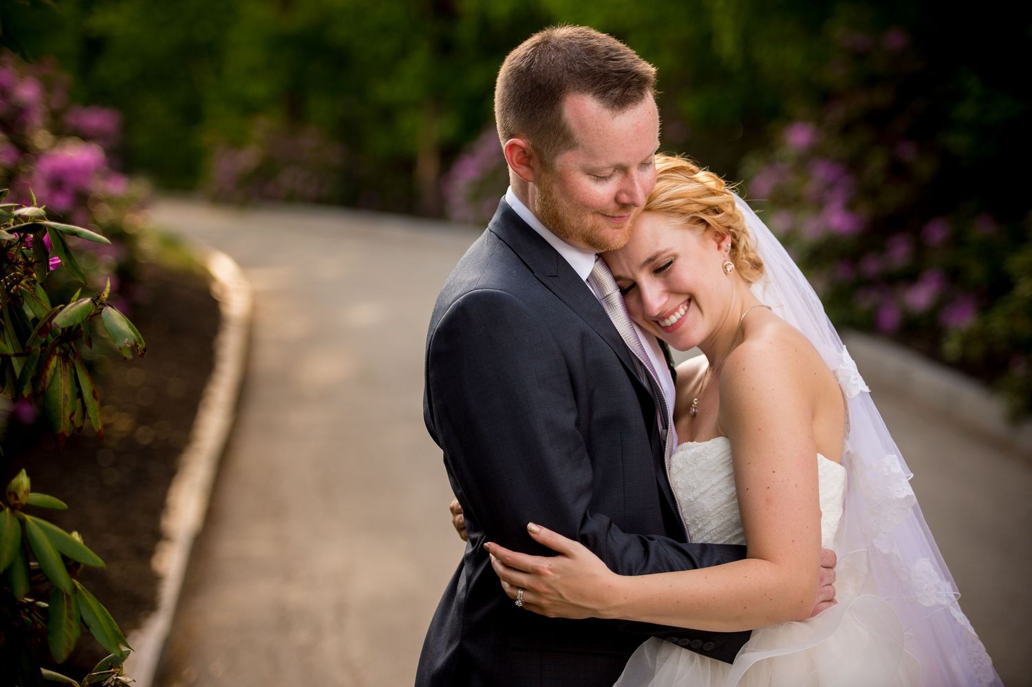 Beautiful garden wedding photo session with blooming pink flowers in background.