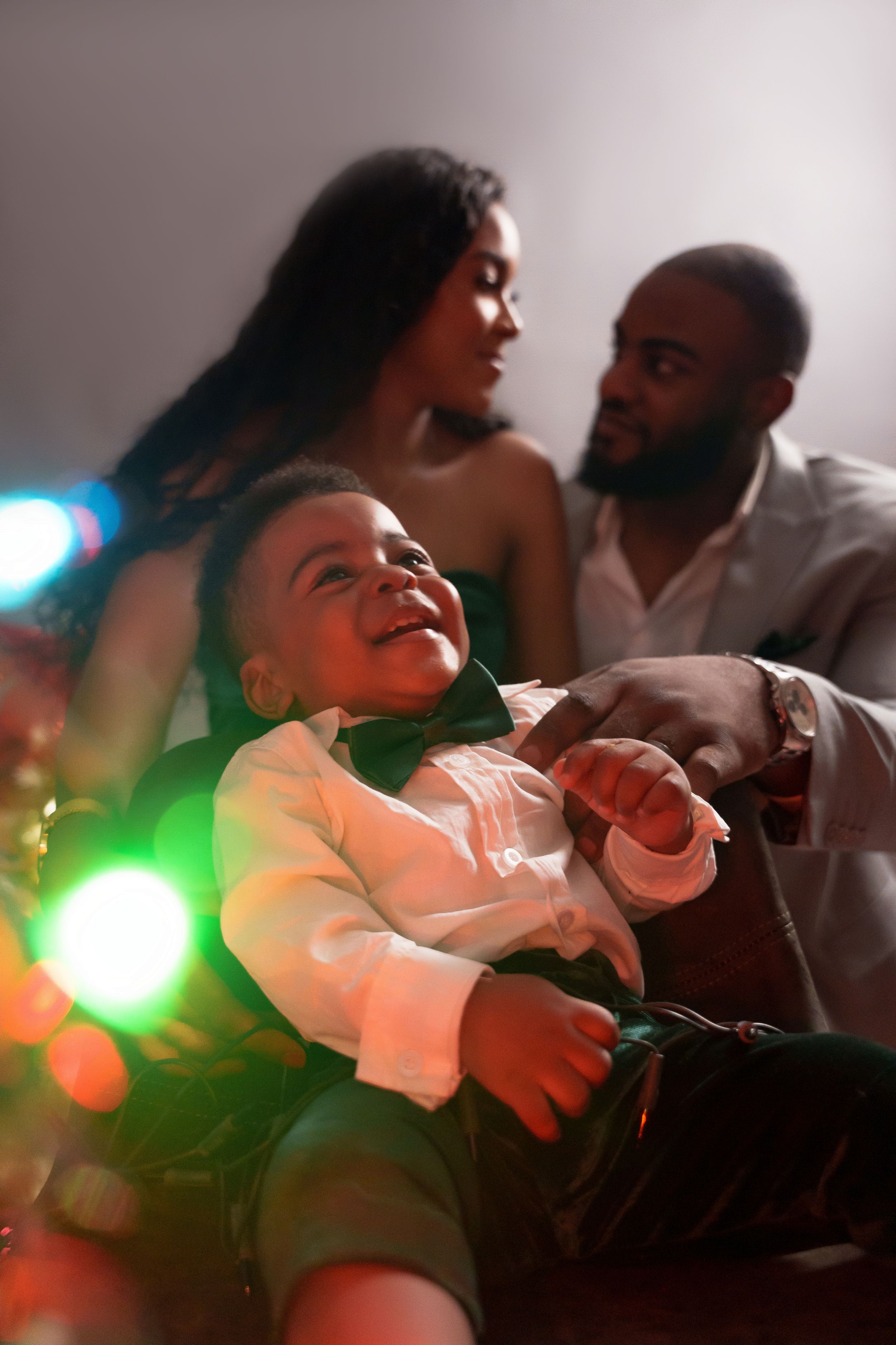 Candid family moment with holiday lights creating warm bokeh effect in background.