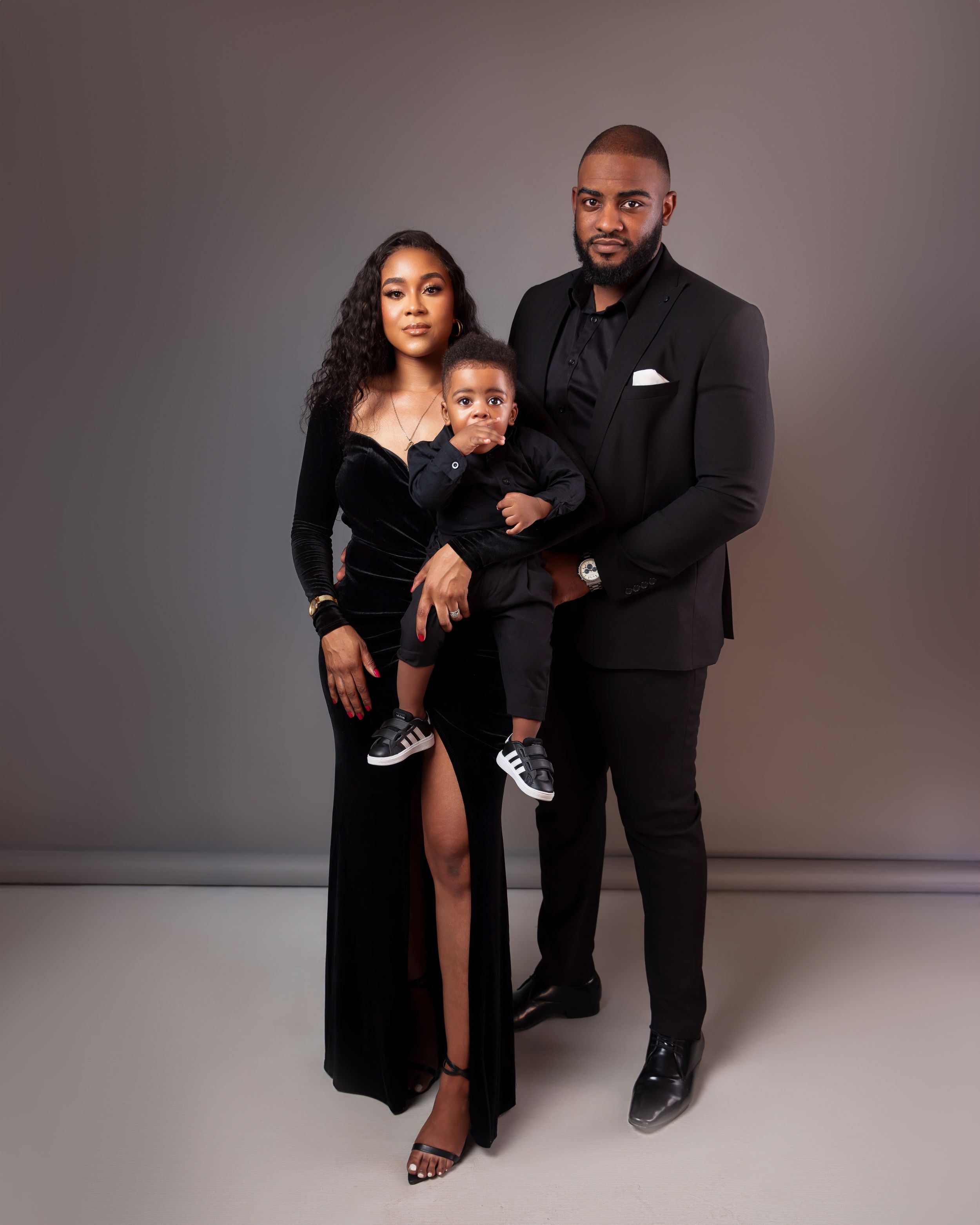 Elegant family portrait in formal black attire against studio backdrop.