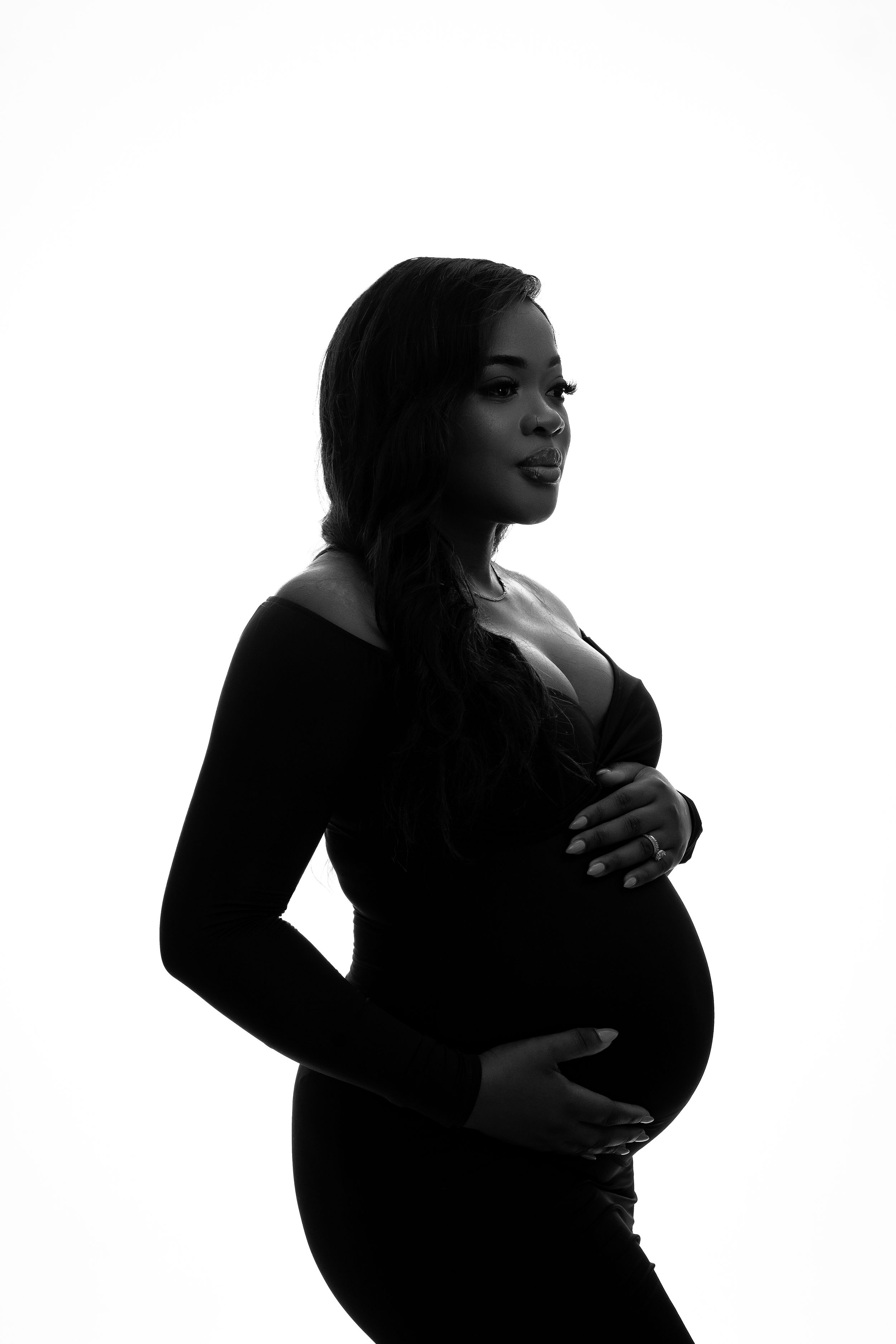 Side profile silhouette of expectant mother in black dress against white background.
