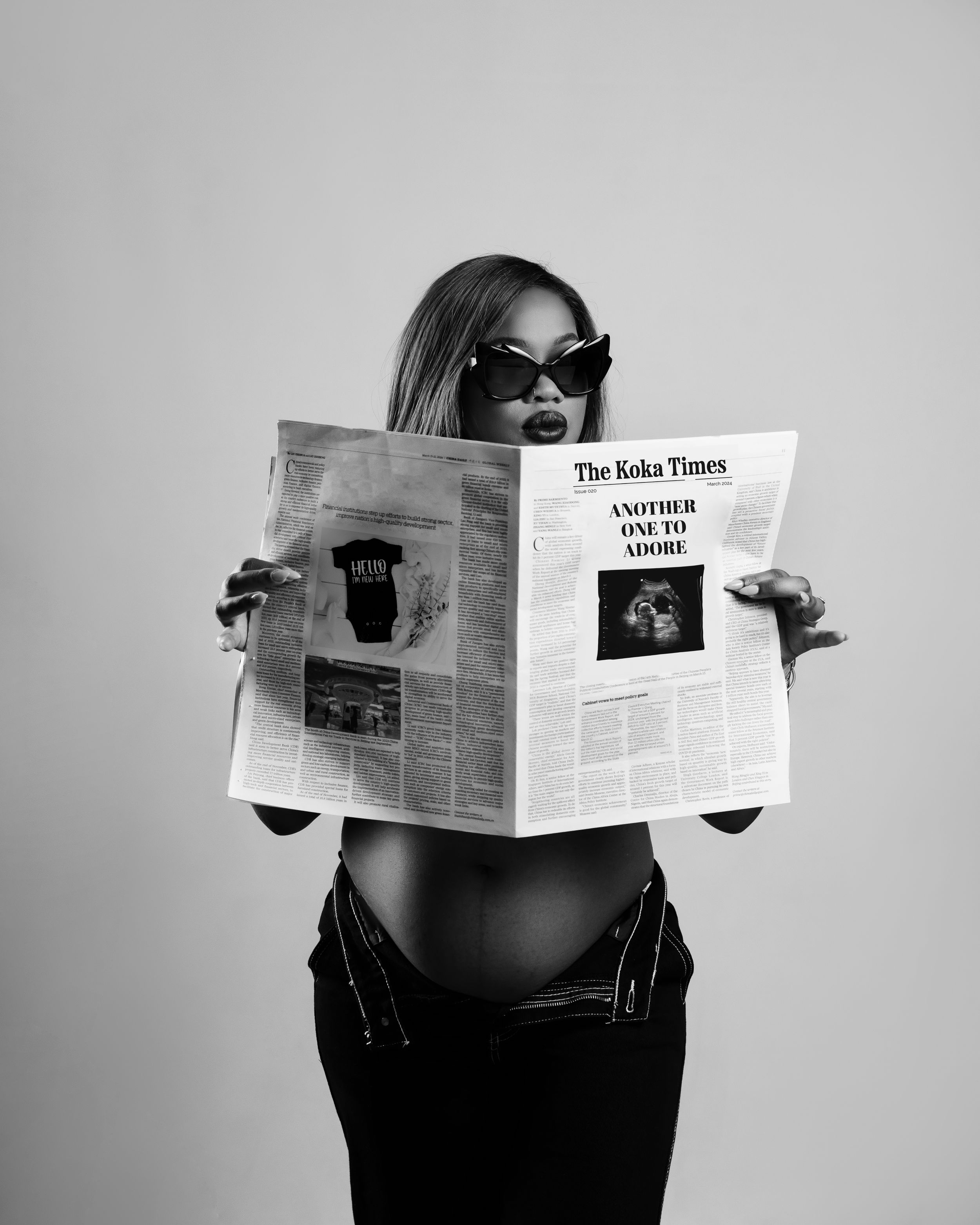 Creative maternity photo with subject reading newspaper while wearing sunglasses.