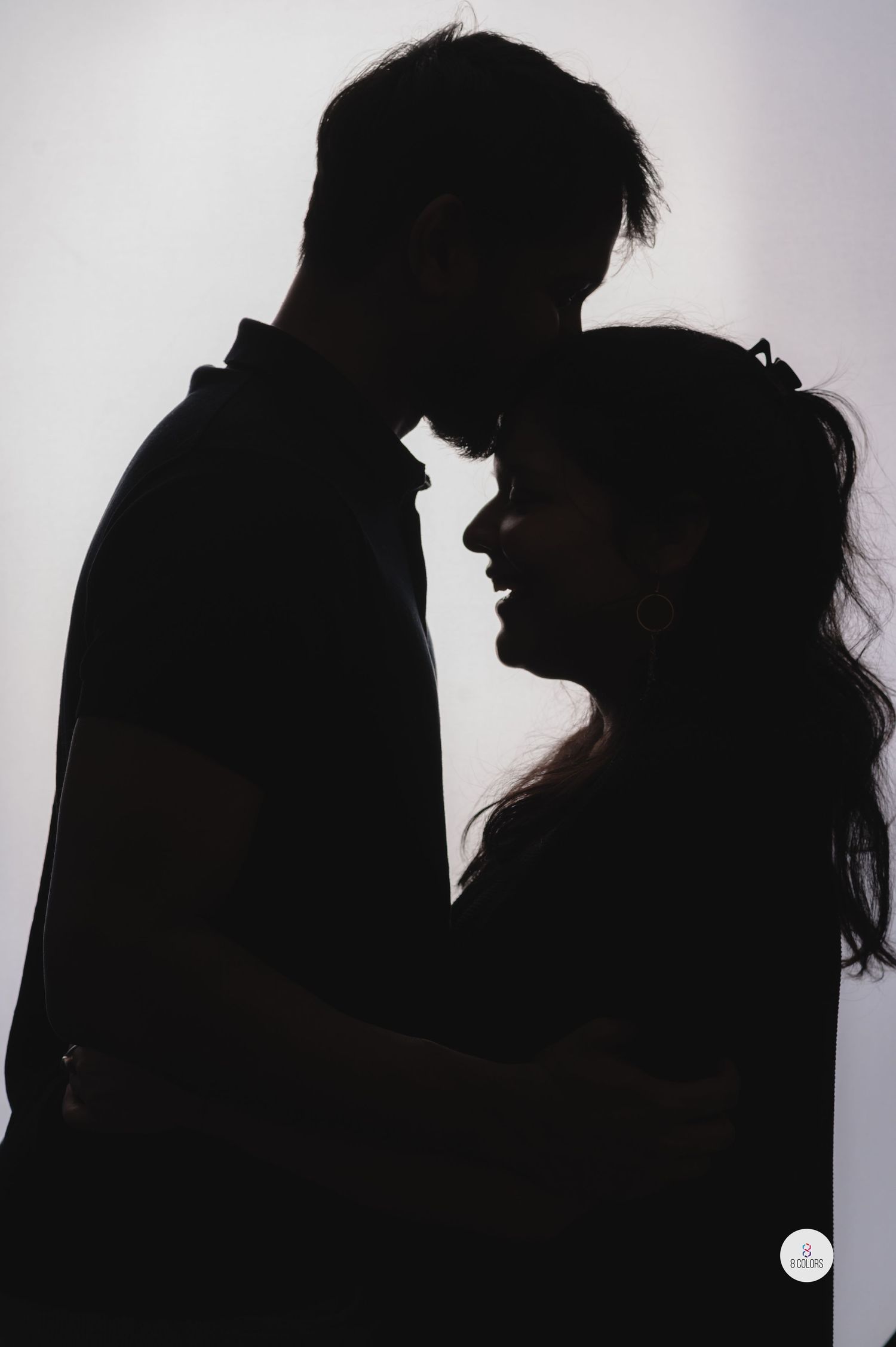 Romantic silhouette of a couple in an intimate embrace against a light background.