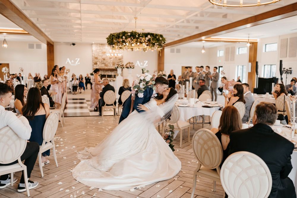 Bride and groom share their first dance in an elegant wedding reception hall with floral chandelier.