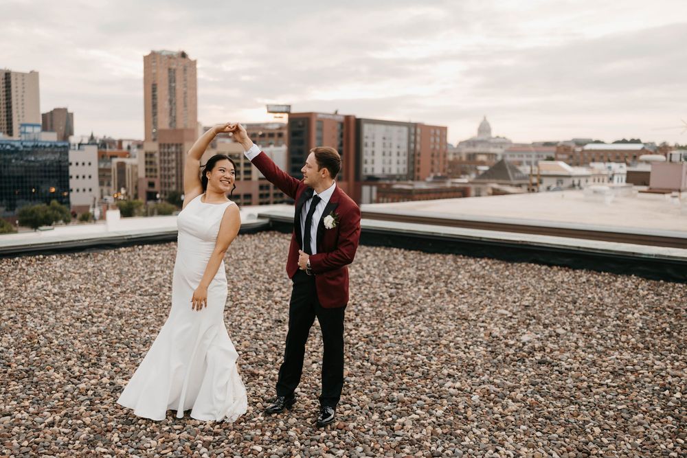 Bride and groom dancing on rooftop with city skyline backdrop on their wedding day.