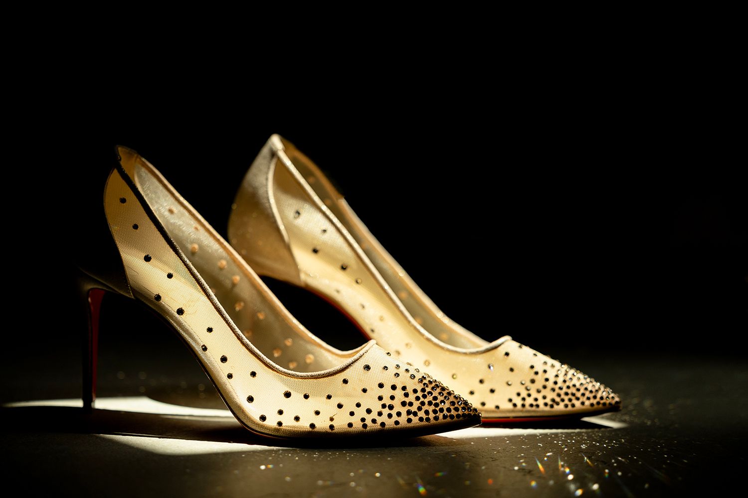 Elegant white bridal shoes with crystal embellishments displayed against dark background.