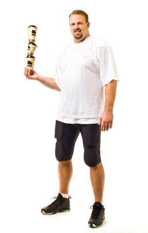 Athletic man in white t-shirt and shorts holds a stacked set of cups on a white background.