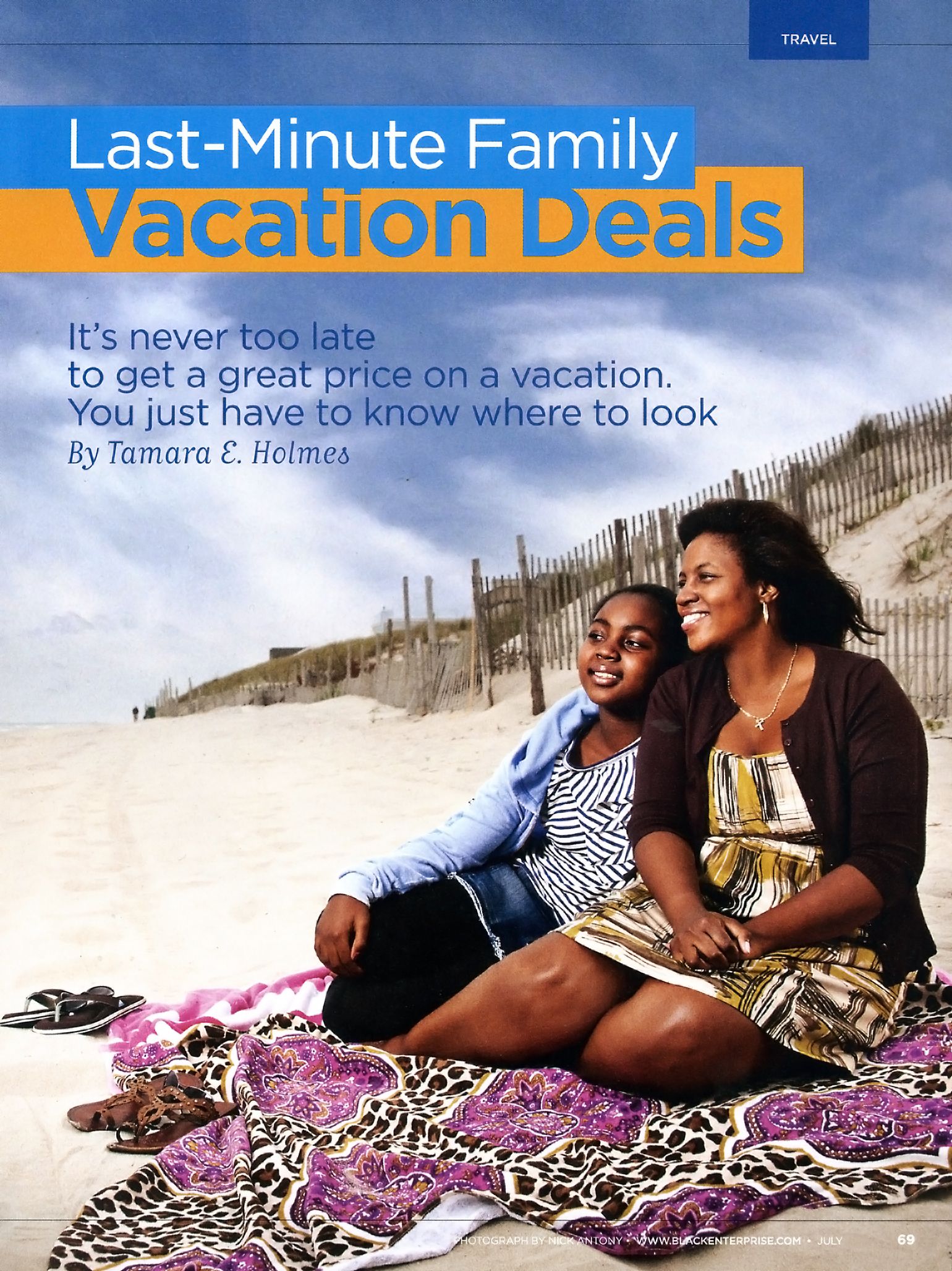 Mother and child sit on beach blanket in sand dunes for Last-Minute Family Vacation Deals article.