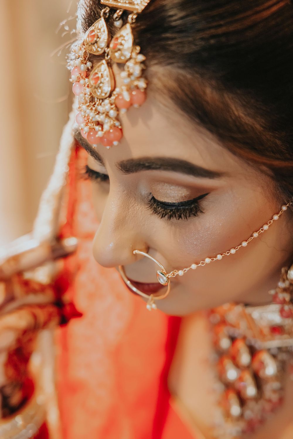 Close up of Indian bridal makeup and jewelry with traditional nose ring and headpiece.