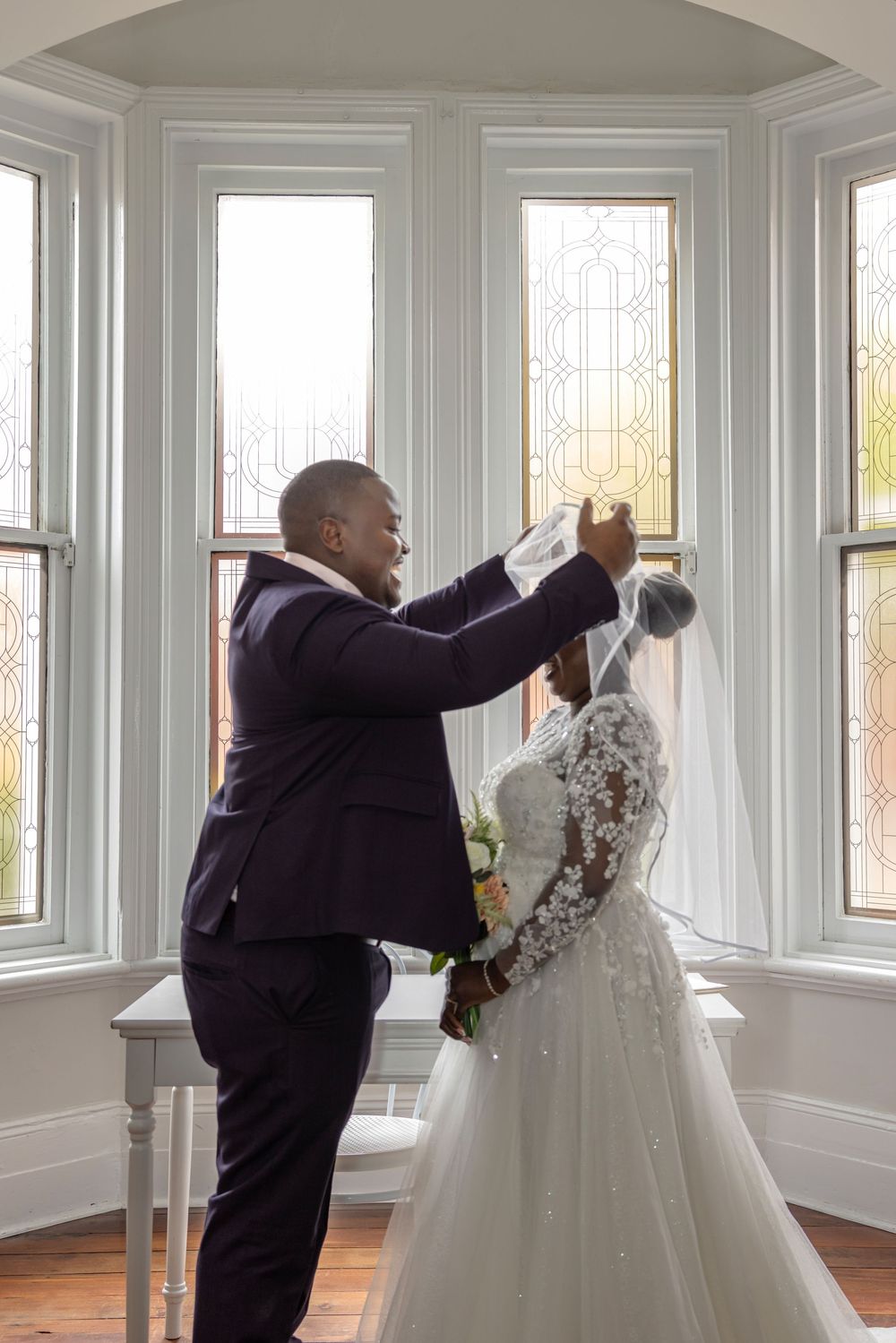 A sequence showing a person in a black suit inspecting and dusting off a white wedding dress displayed by the window.
