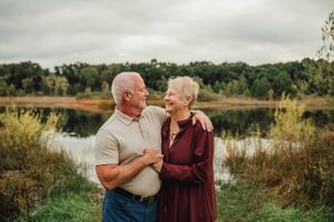 Senior couple sharing intimate moment by lakeside during autumn season.