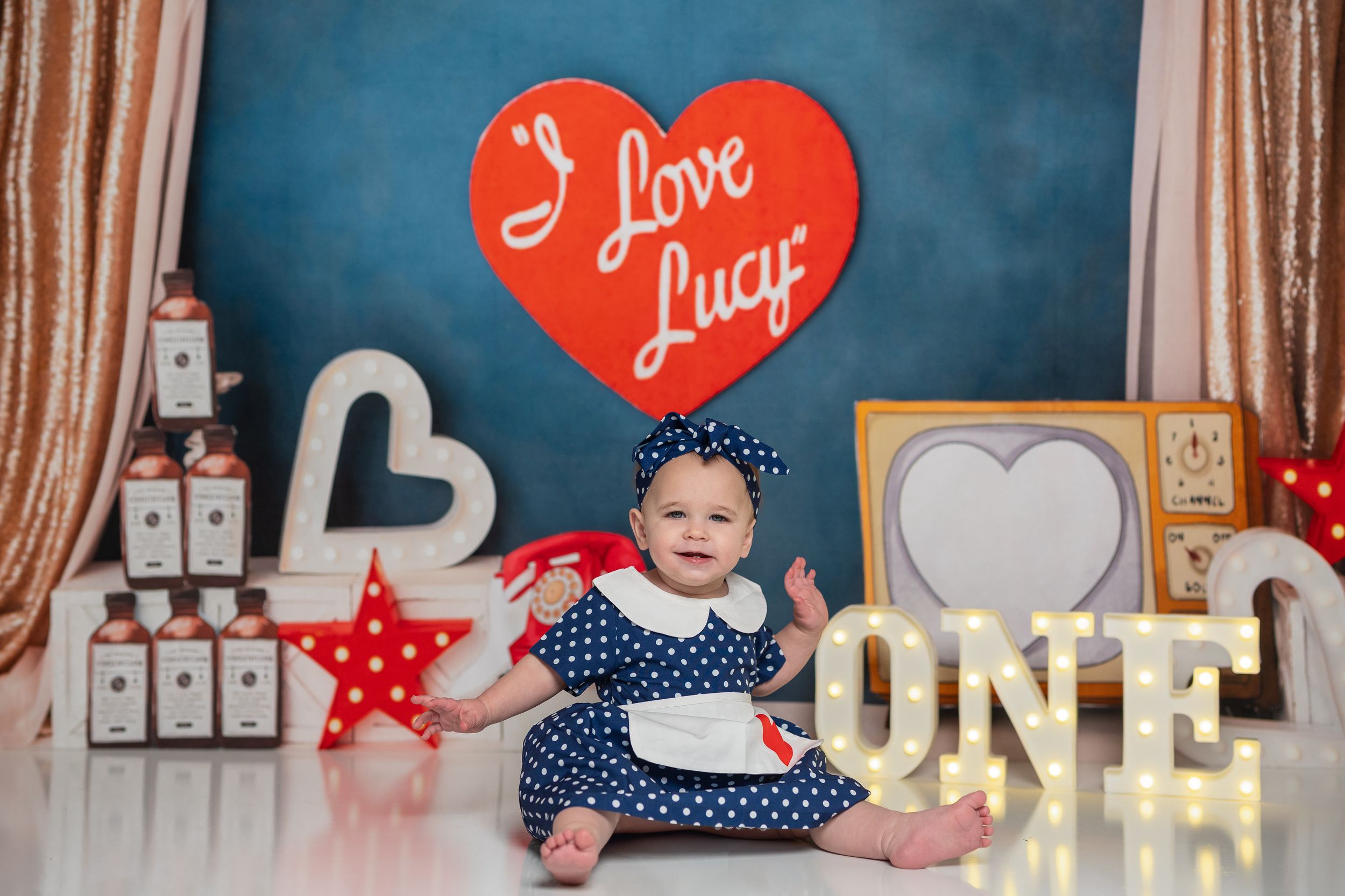 A Valentine's Day themed party setup with red heart decorations, polka dot patterns, and white lettering against wood paneling.