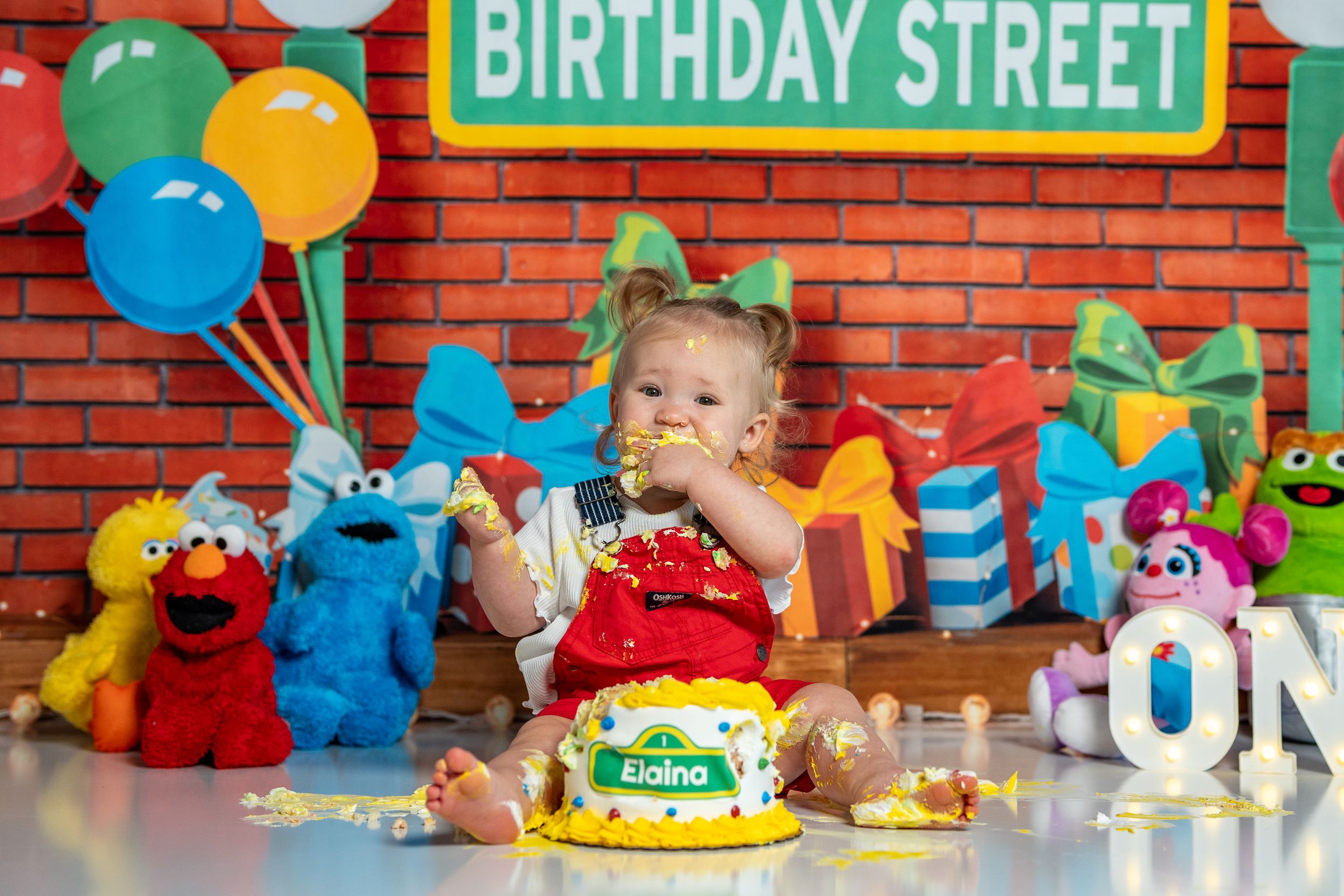 First birthday cake smash photo with Sesame Street decorations and balloons.