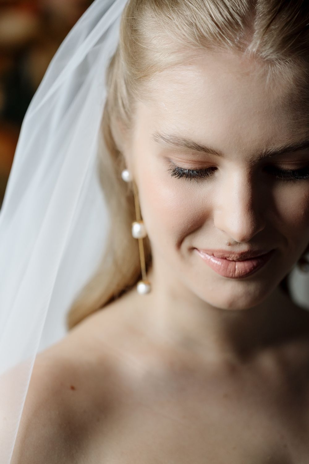 Soft, romantic close-up portrait showing delicate bridal details and veil.