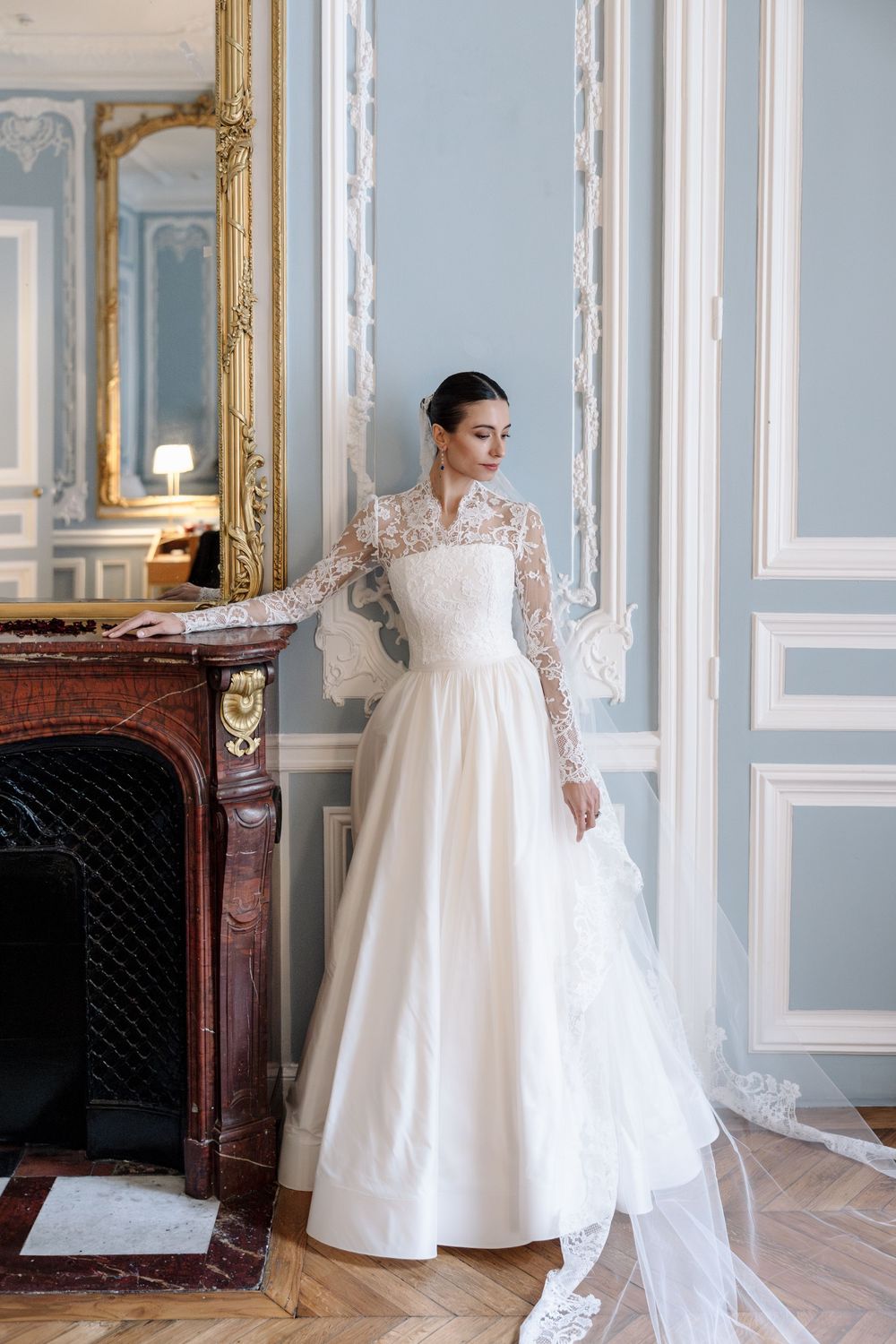 Classic long-sleeve lace wedding gown photographed in an elegant blue and gold French salon.