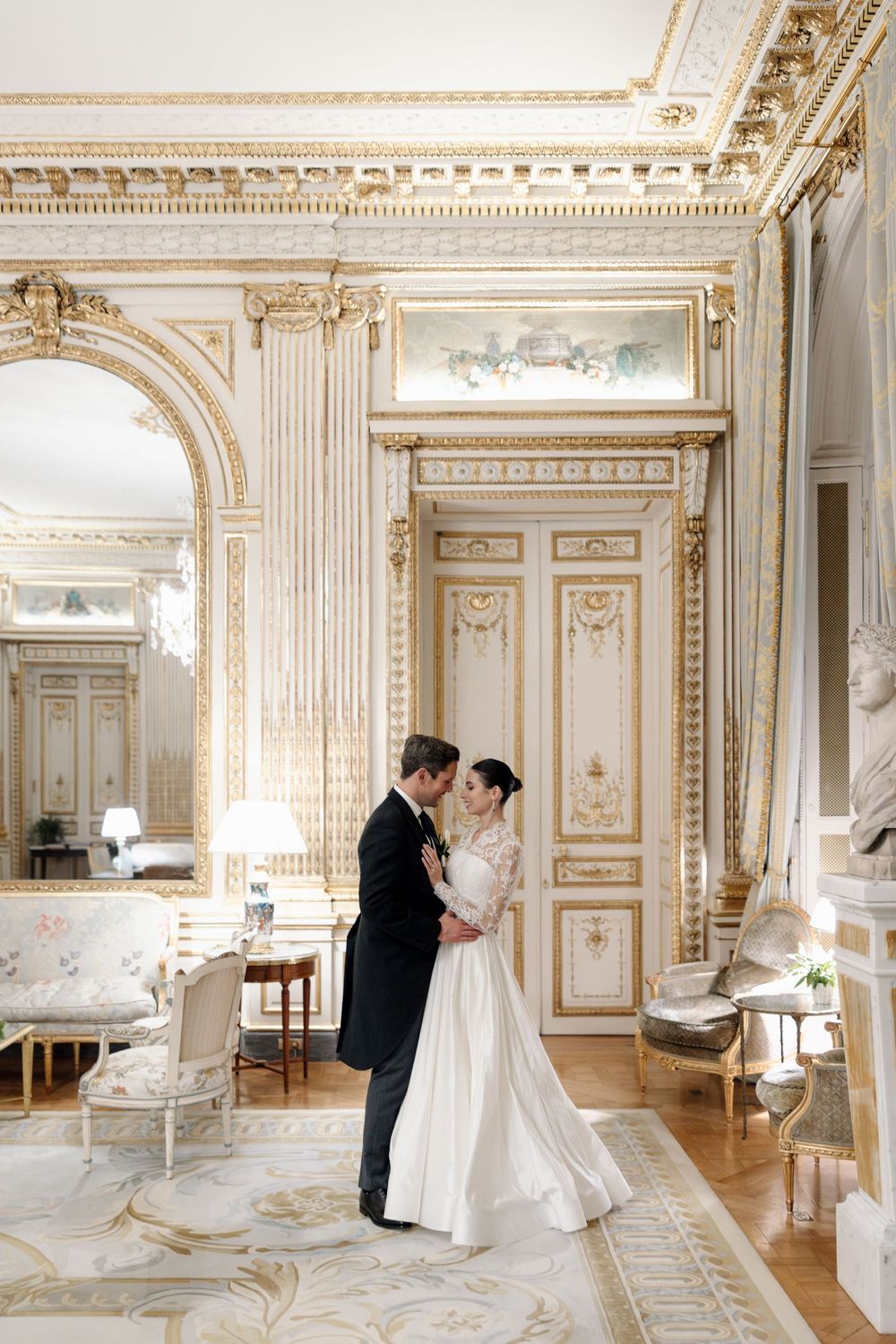 Elegant wedding moment in an ornate French palace room with gilded details and classical architecture.
