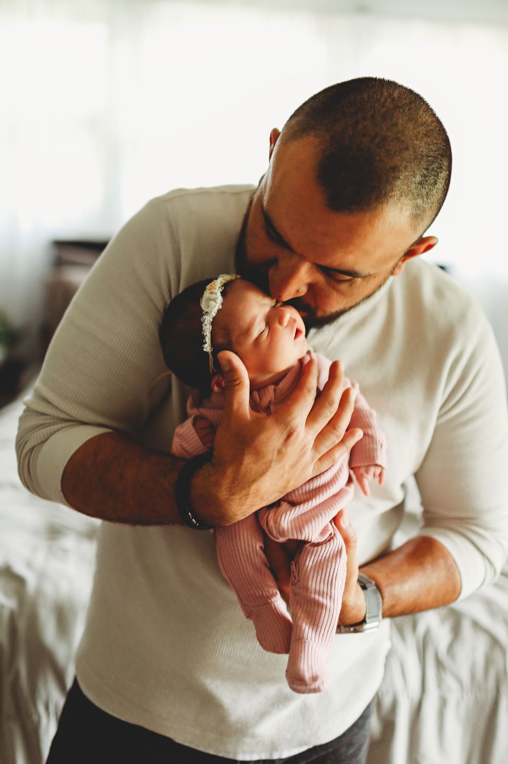 Daddy snuggle baby girl close to his face and kissing her