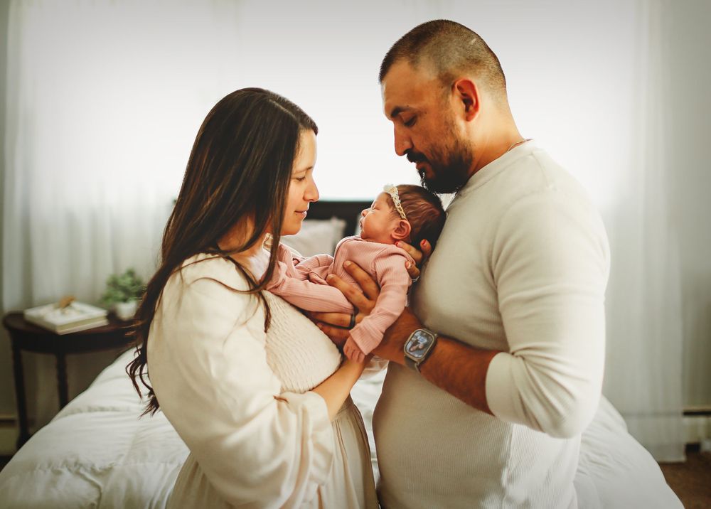 A tender moment as parents gaze lovingly at their newborn baby in a cozy bedroom.