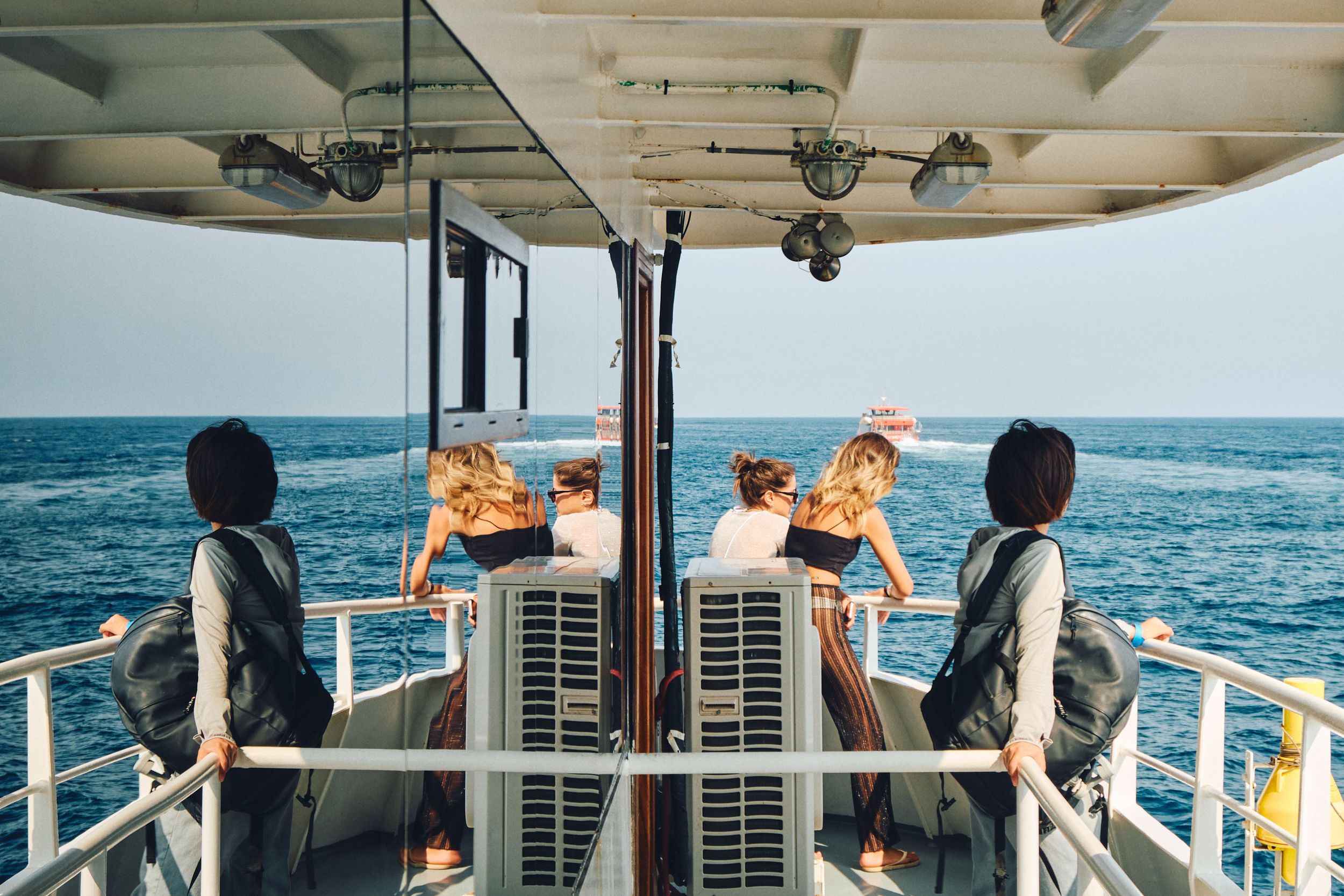 Passengers enjoying boat trip on Mediterranean waters with equipment and safety gear visible.
