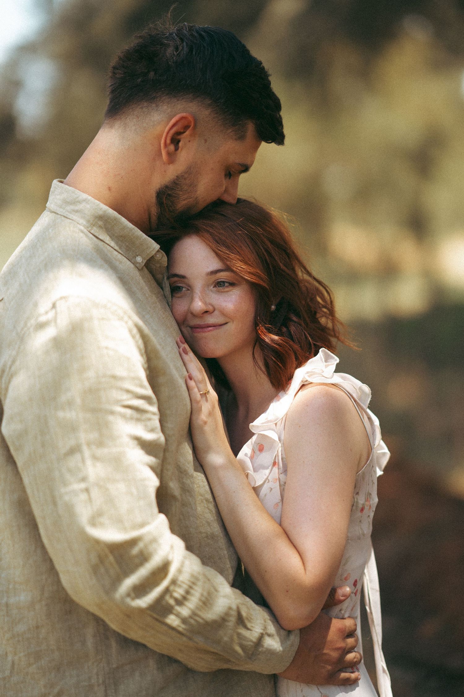 A romantic moment captured between two people in warm lighting outdoors.
