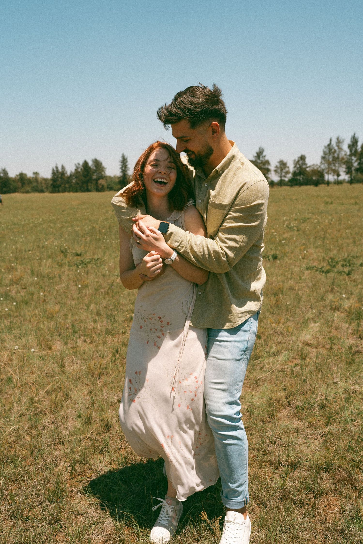 A candid moment of laughter and joy between two people dancing in a field.
