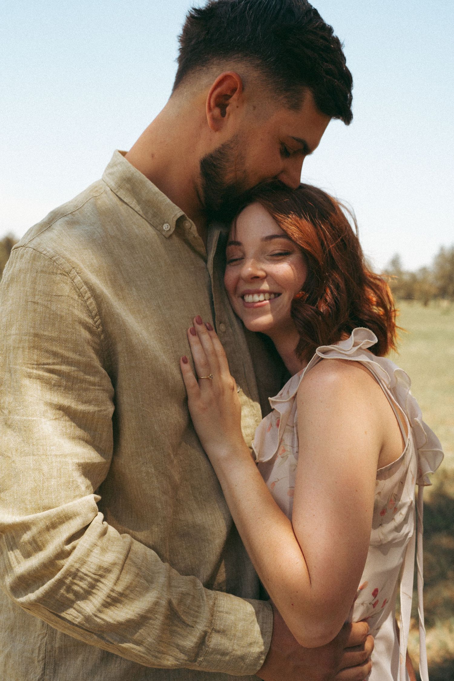Intimate outdoor portrait of couple sharing tender moments in warm sunlight.