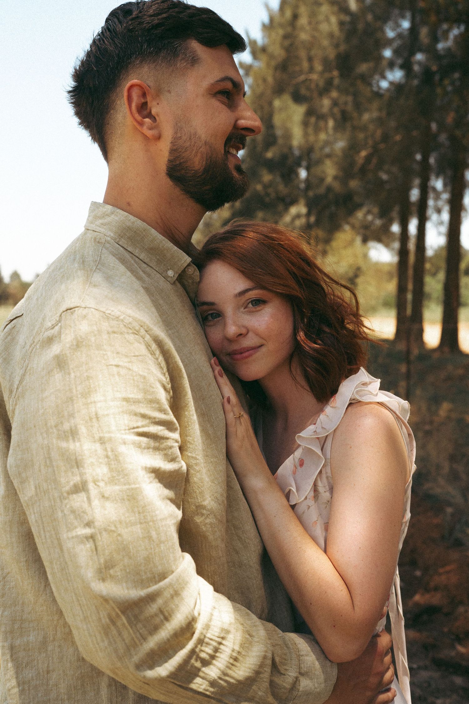 Couple in casual attire shares affectionate moments against a natural outdoor setting.