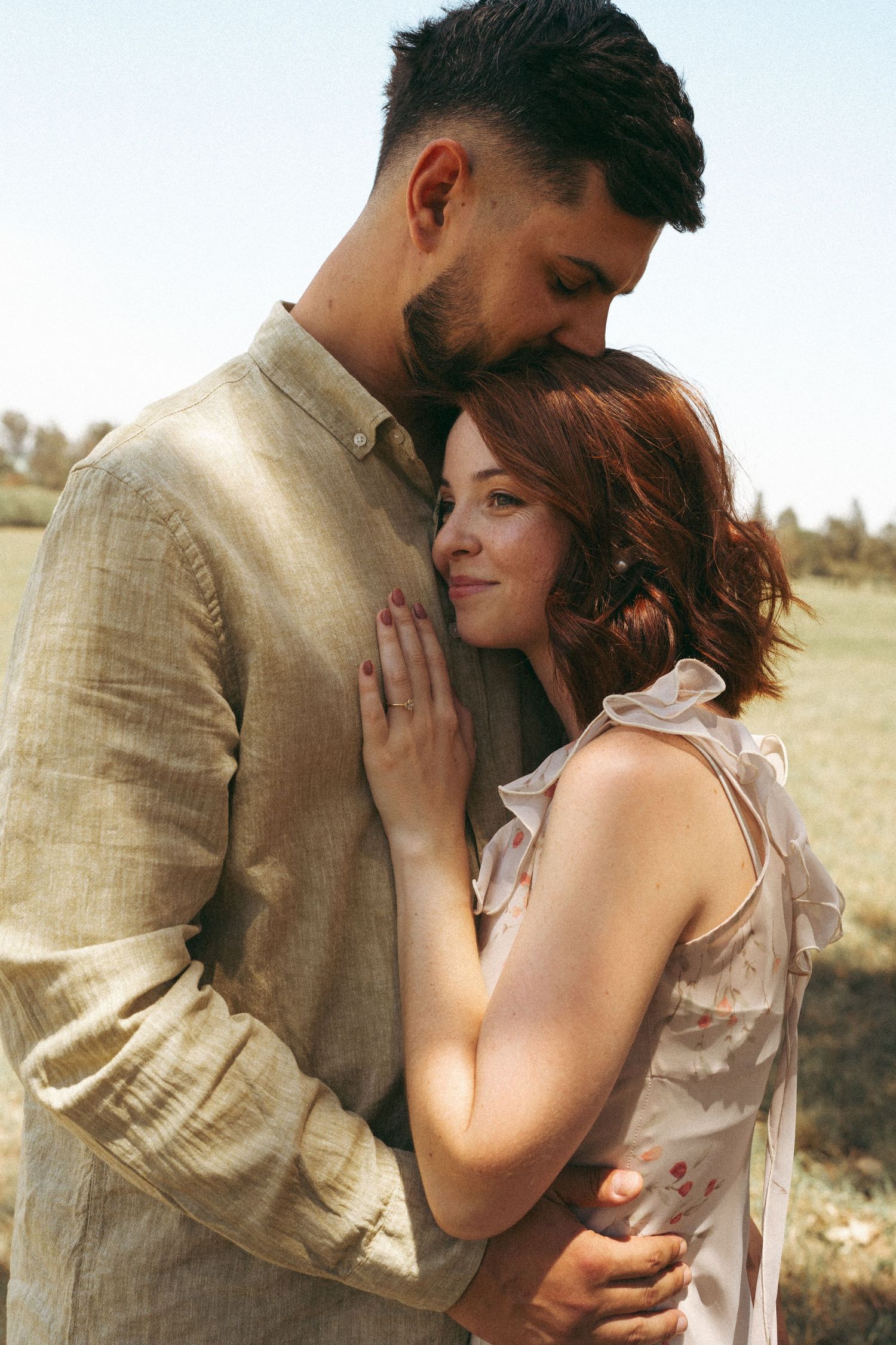 Couple shares tender embraces in golden afternoon light outdoors.