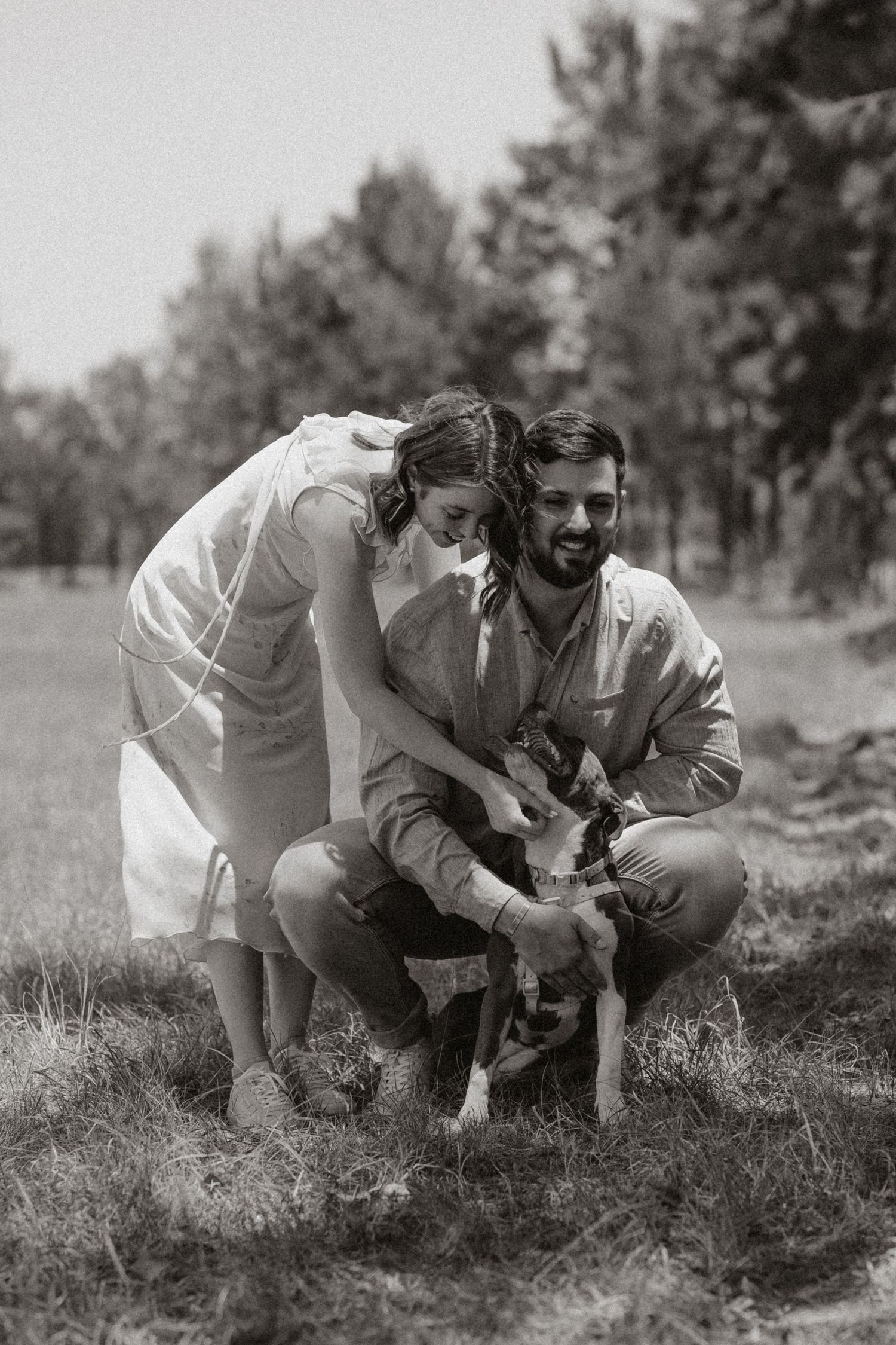 Black and white photo of couple discovering something interesting in a field.