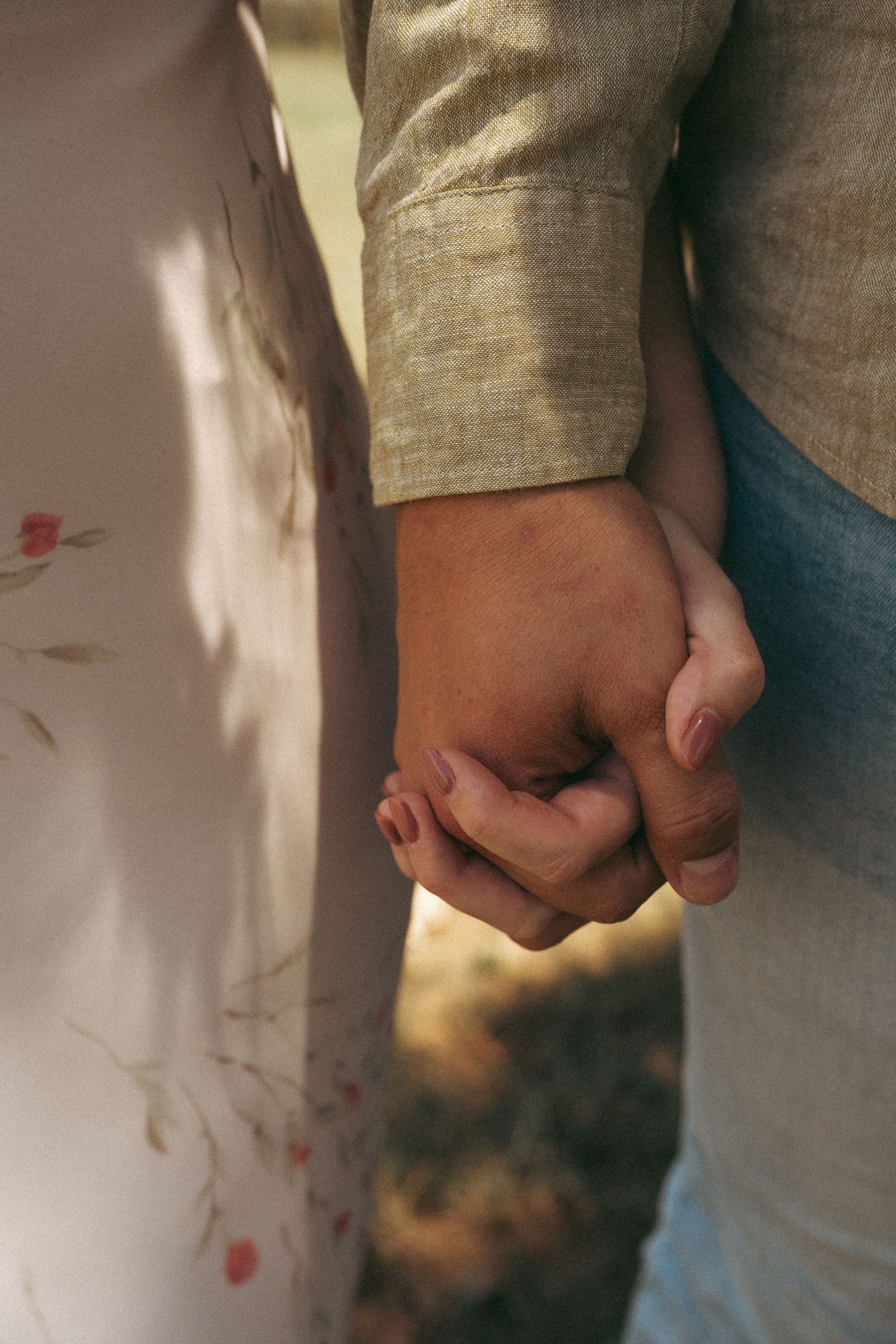 Close-up of hands holding together in a romantic gesture against a light background.