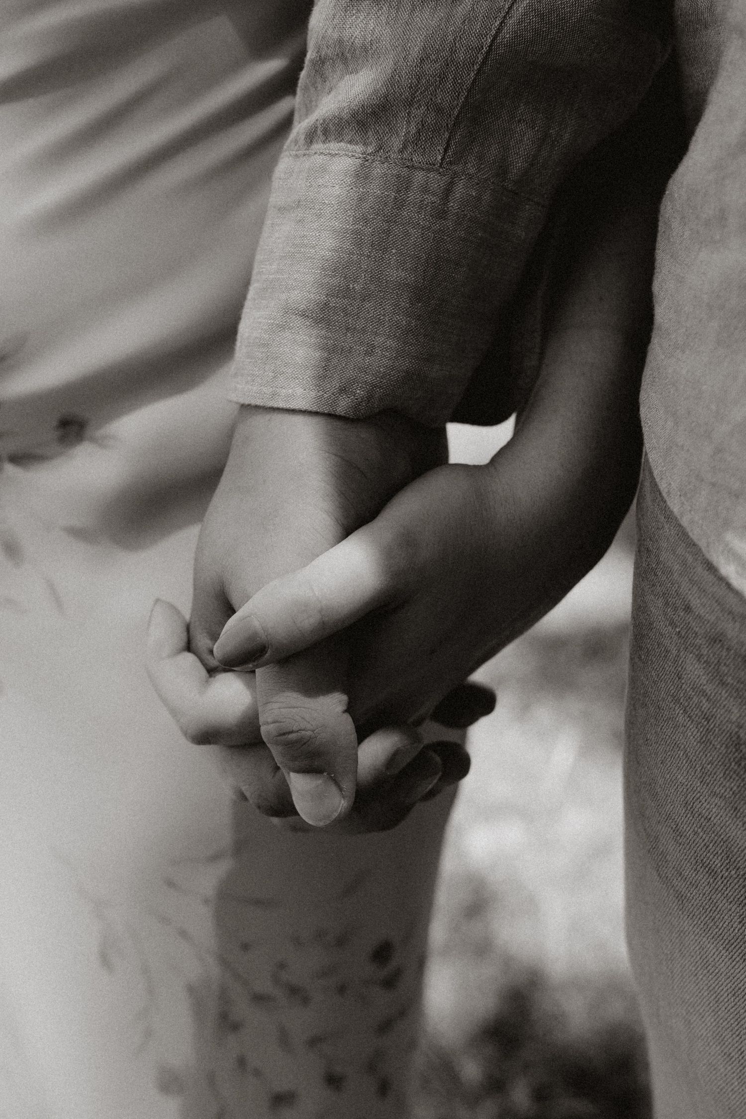 Artistic black and white close-up of hands intertwined.