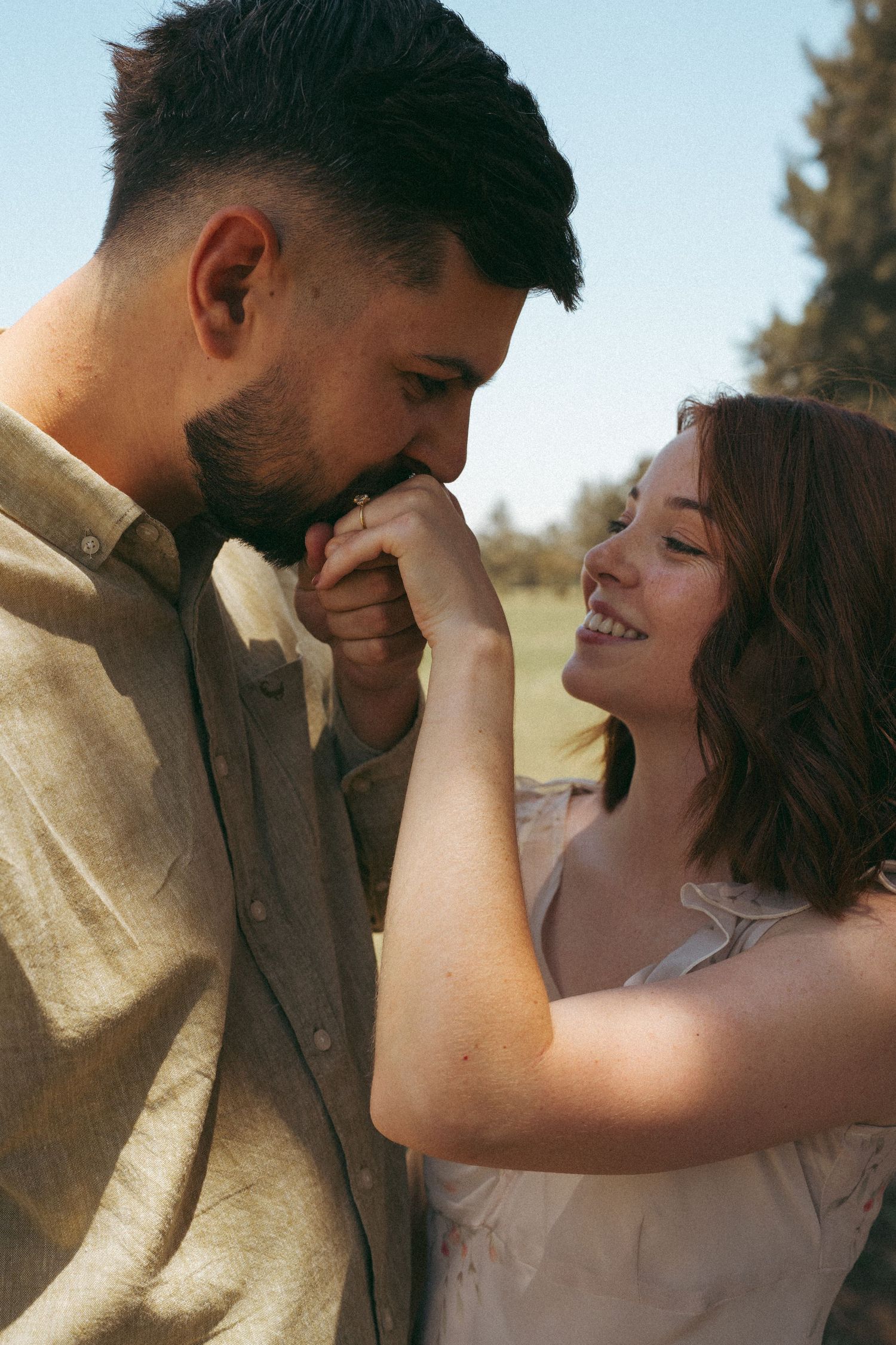 Intimate moment between a couple sharing laughter and joy in natural sunlight.