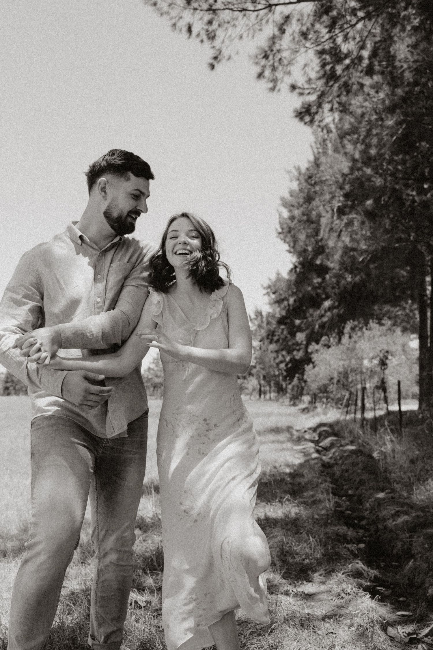 Candid moment of a couple laughing together in a natural outdoor setting.
