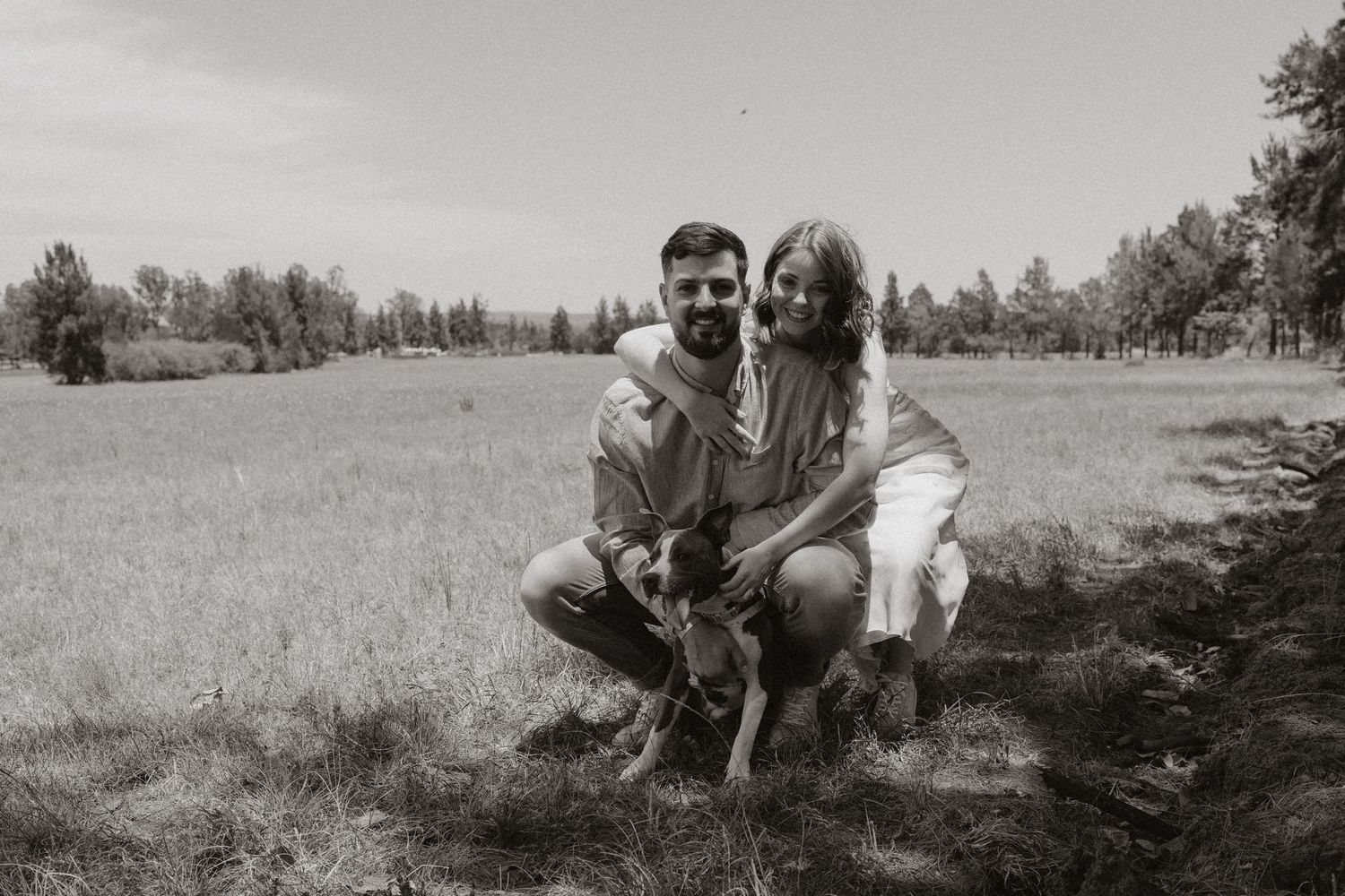A black and white photo series capturing intimate moments between a couple in a meadow.