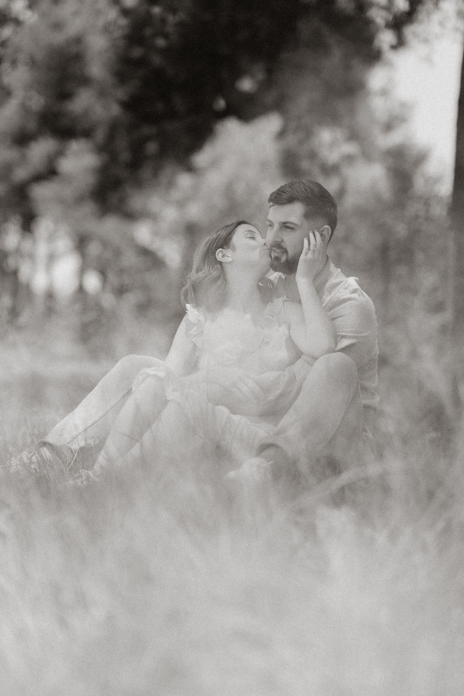 Dreamy black and white photo of a couple embracing in tall grass.