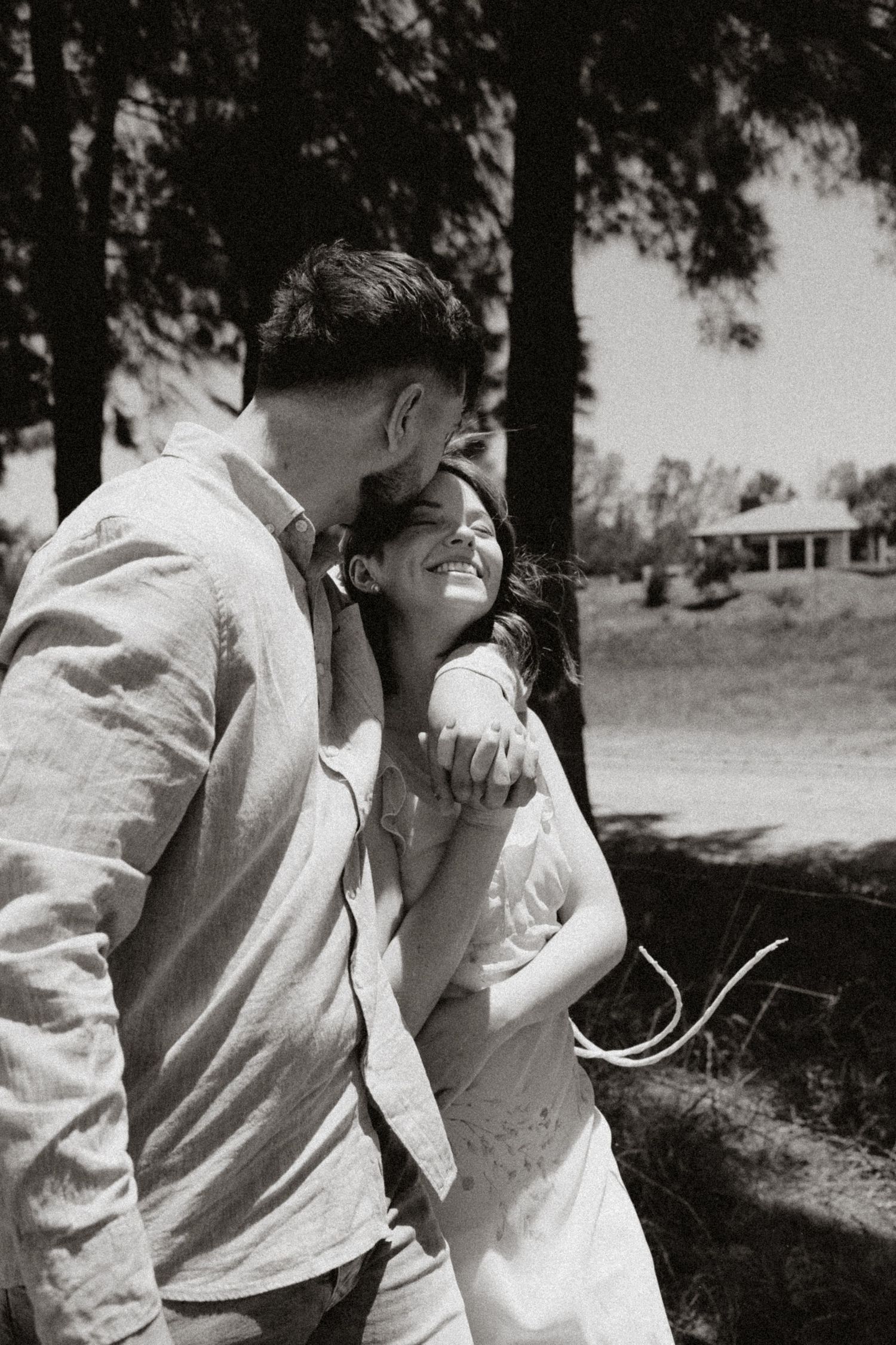 Black and white photo capturing intimate moments between a couple outdoors.