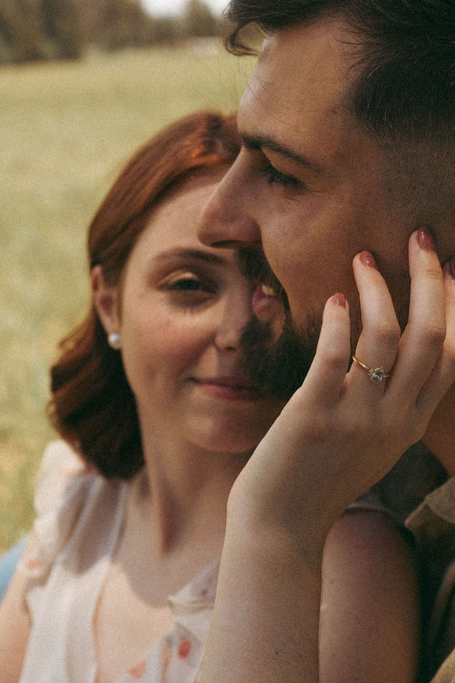 A tender close-up moment between a couple in a golden field at sunset.