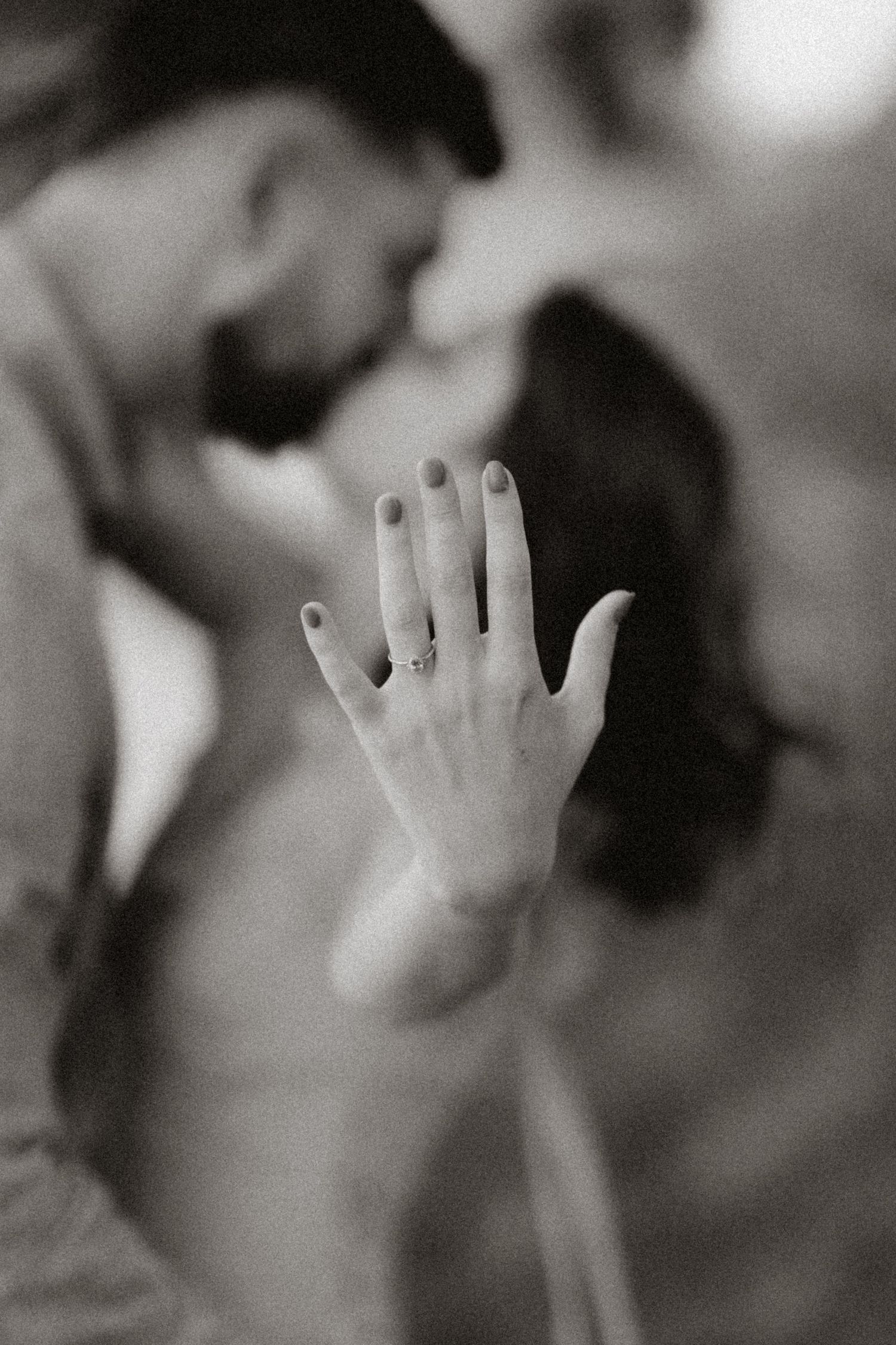 A close-up black and white photo showing a hand with an engagement ring.