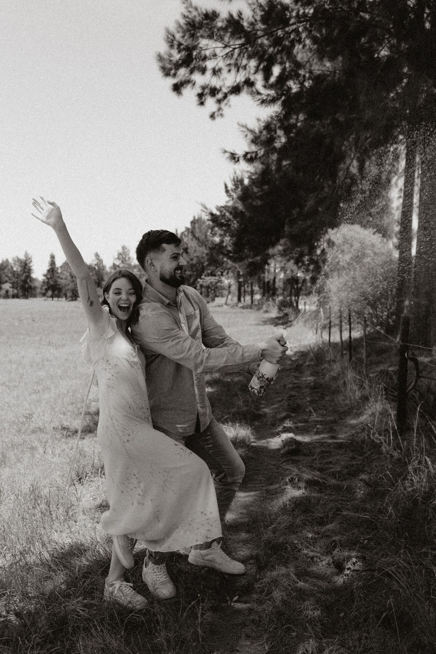 A joyful black and white photo of a couple celebrating in nature.