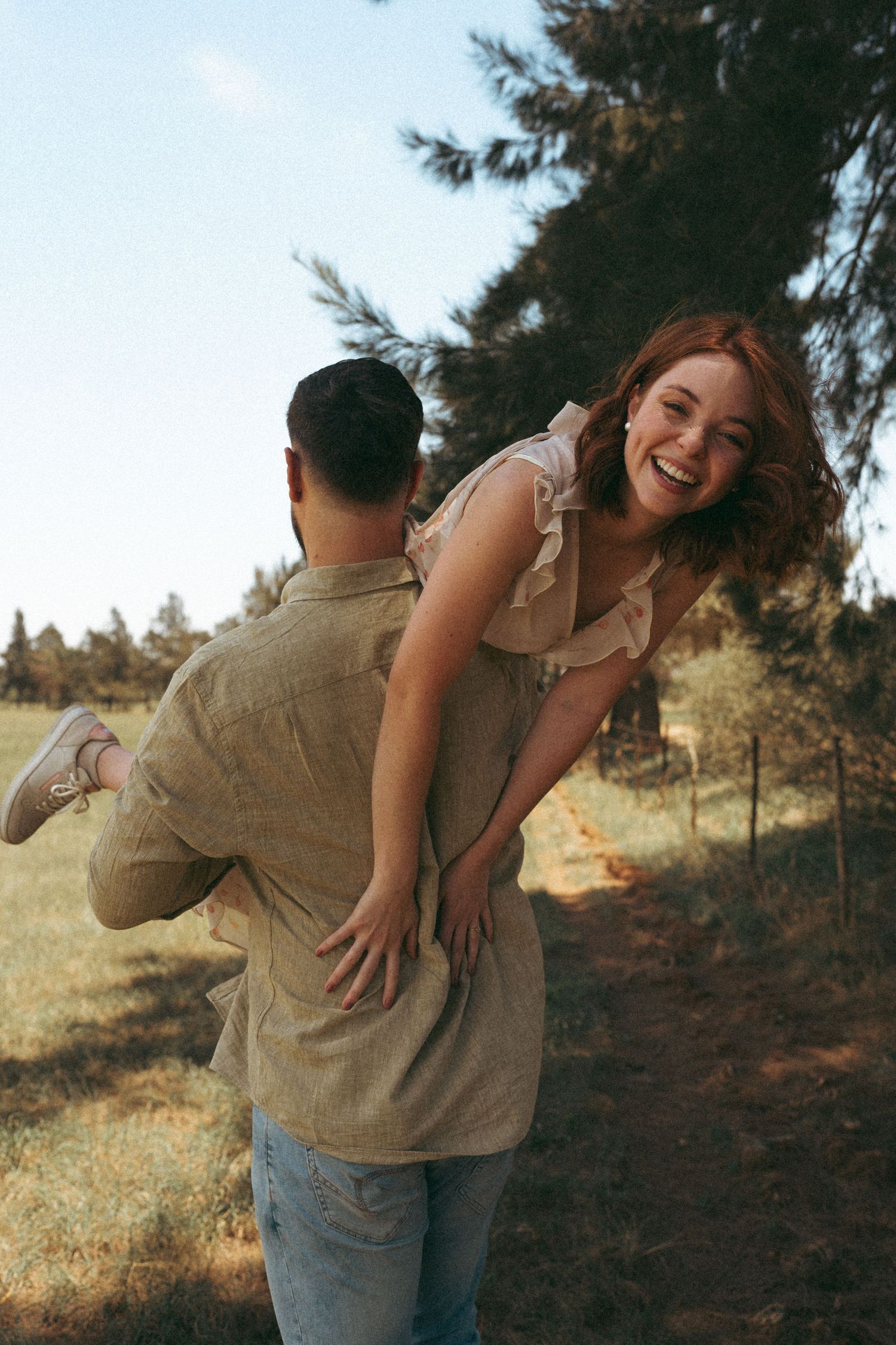 A playful piggyback ride moment captured in warm sunlight near pine trees.